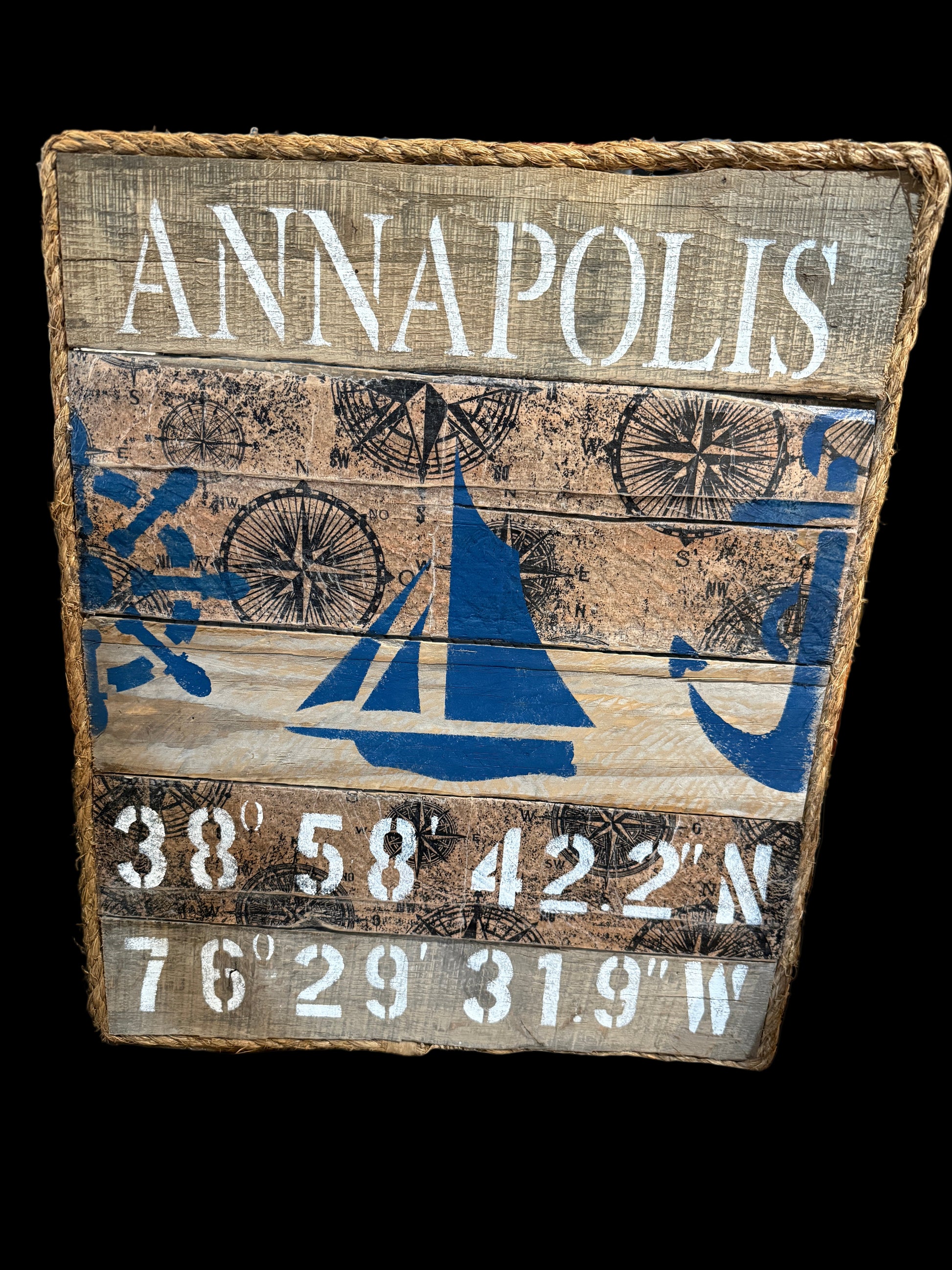 Wooden sign with 'Annapolis' and nautical designs on a wooden surface.