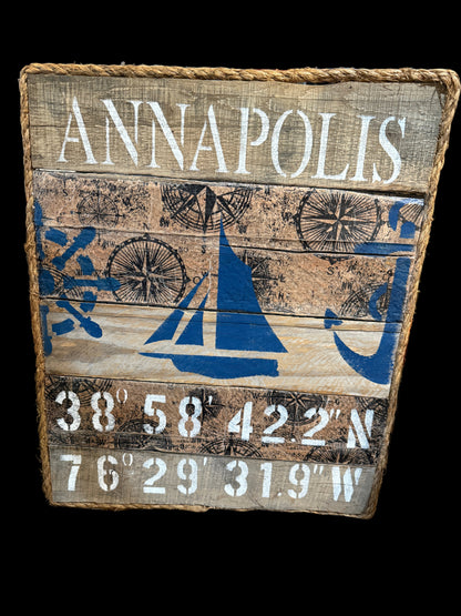 Wooden sign with 'Annapolis' and nautical designs on a wooden surface.